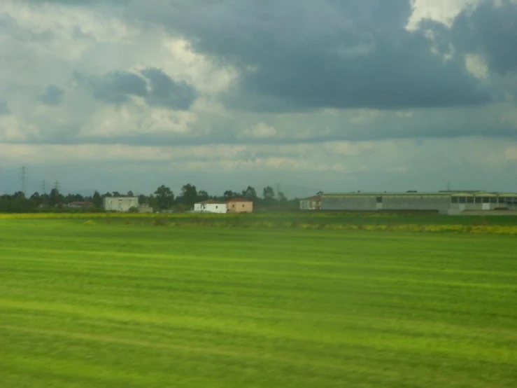 a field with some buildings in the distance