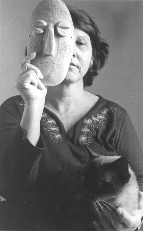 black and white pograph of woman holding a mask with a cat