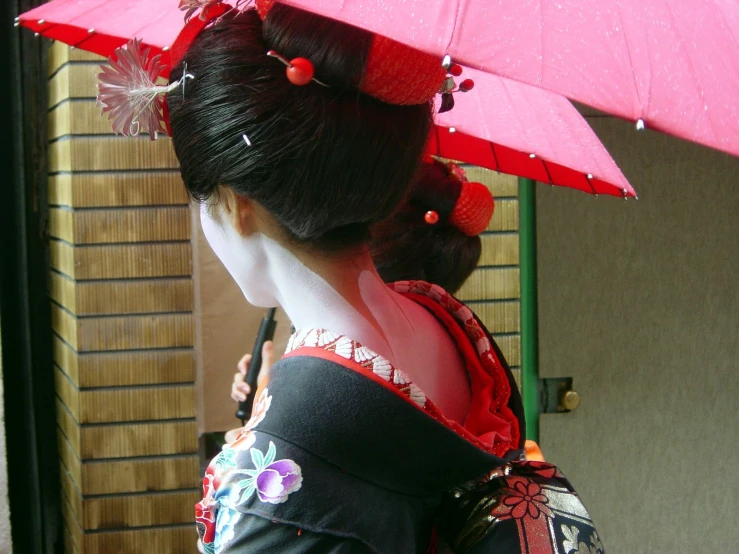 the woman in traditional asian clothing is holding her umbrella