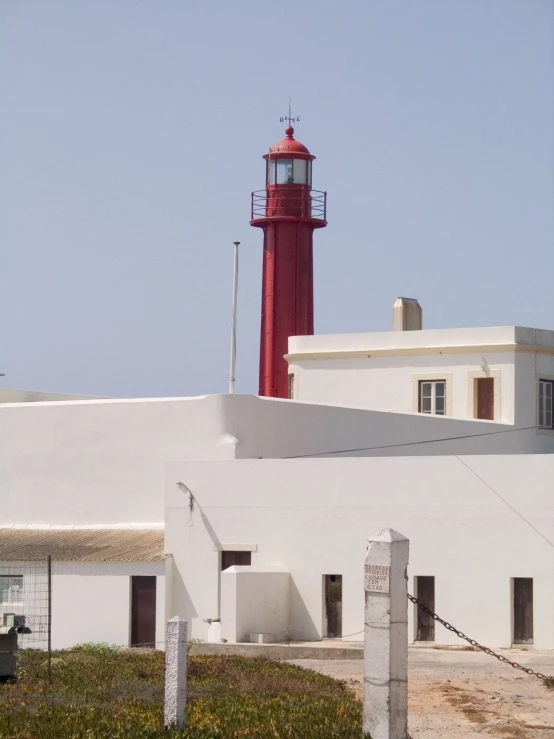 a lighthouse in the distance with a white building in the foreground