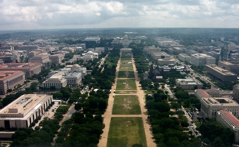 a wide park between two buildings with lots of trees in the middle