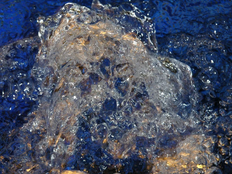 water flowing over rocks from under a cliff