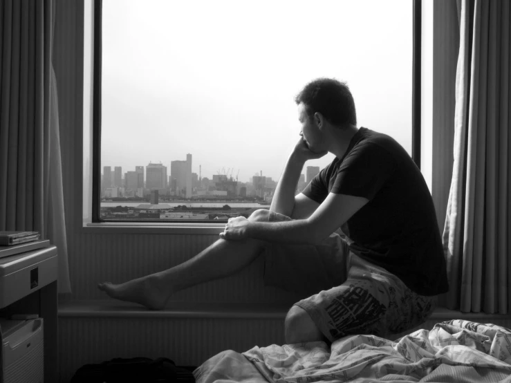 a man sitting in a window sill looking out