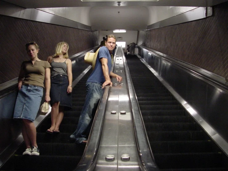three people are riding down an escalator in a public building