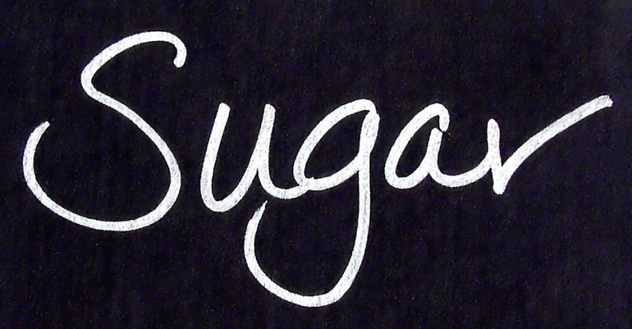 the letters sugar are handwritten on a black board