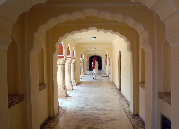 a person walking down a long hallway with arches