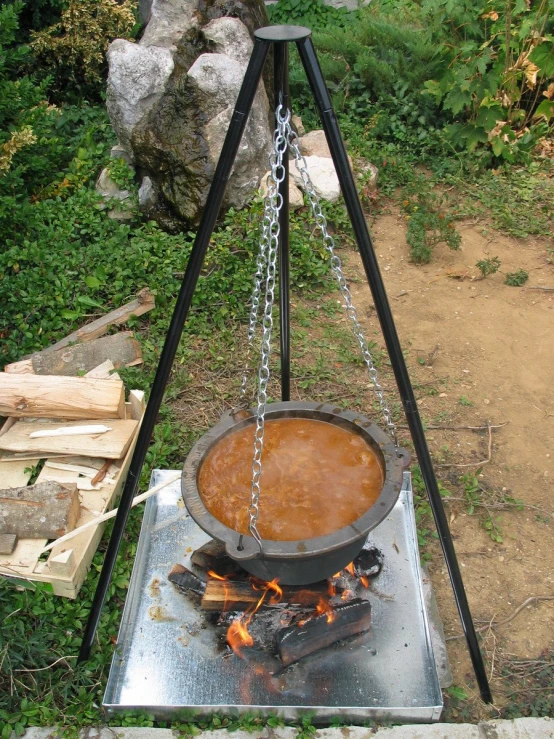a cooking pot over a stove with chains hanging from it