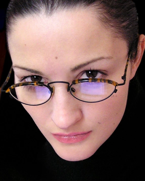 a woman with glasses looks down at soing in her hand