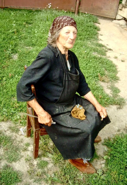 an old woman wearing an apron sitting in a chair