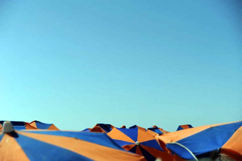 a beach with many orange and blue umbrellas