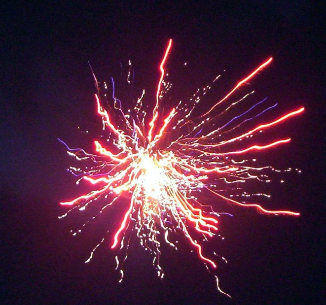 a large fireworks display is glowing brightly red and yellow