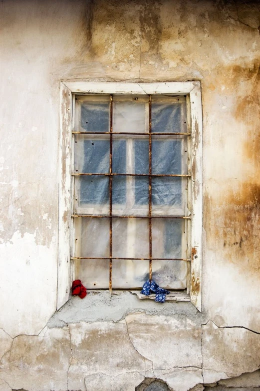 the old window has rusty bars in it