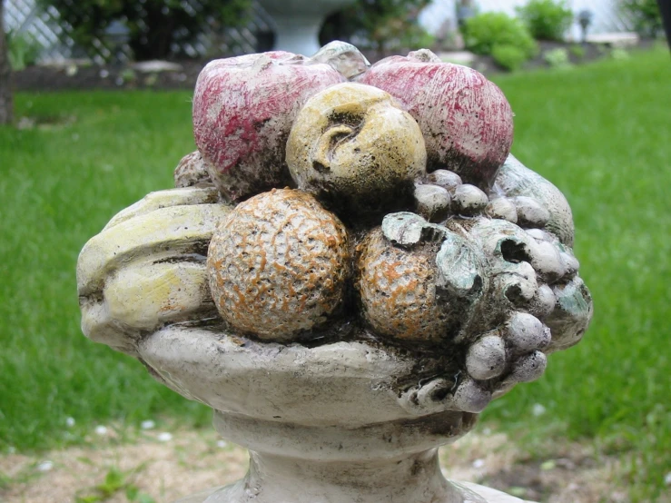 a vase filled with fruits and veggies sitting in the middle of the yard