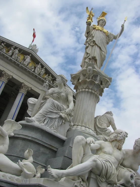 a statue of a woman with a sword and other figures near a building