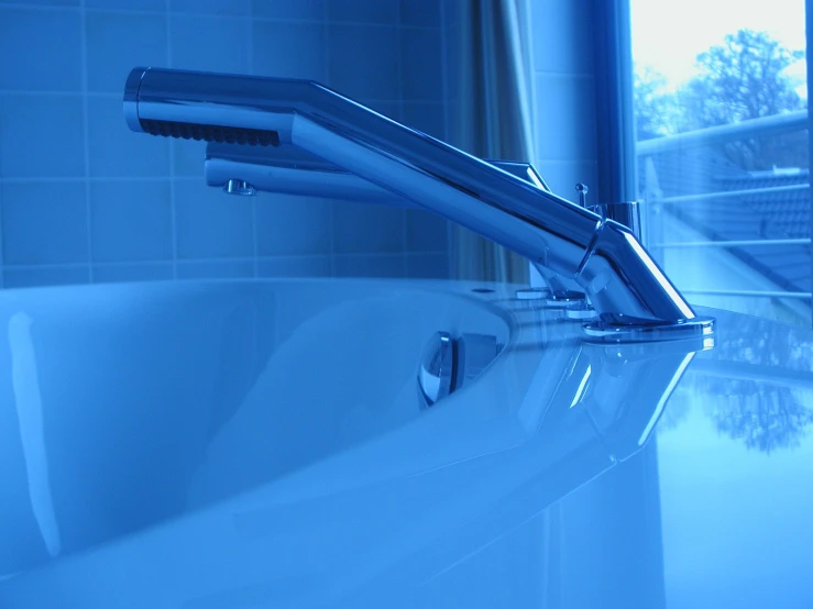 a blue image of two hair brushes on the edge of a bathtub