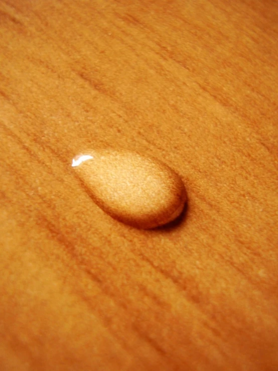 a drop of liquid laying on a wooden surface