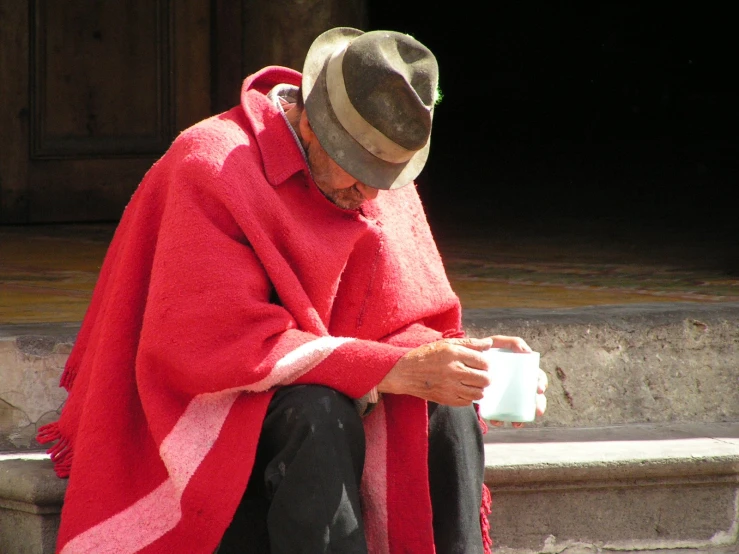 an old man in a ponched sweater drinking coffee