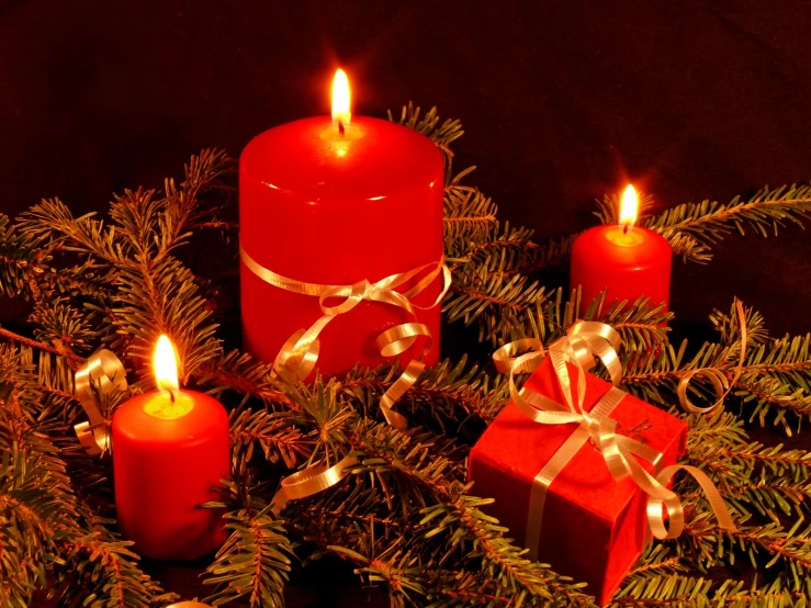 red candles are lit near a tree with presents