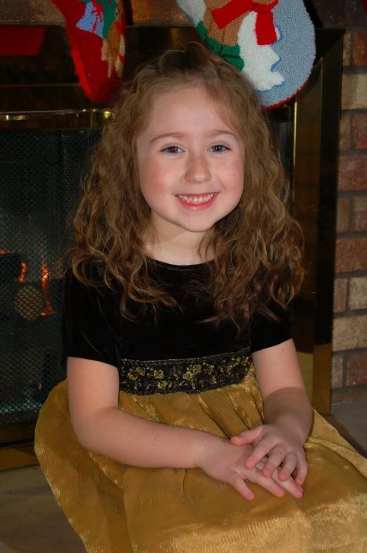 a  sitting on a floor in front of a fireplace