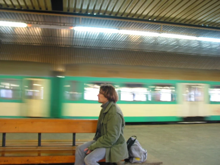 a man sitting on top of a bench near a train