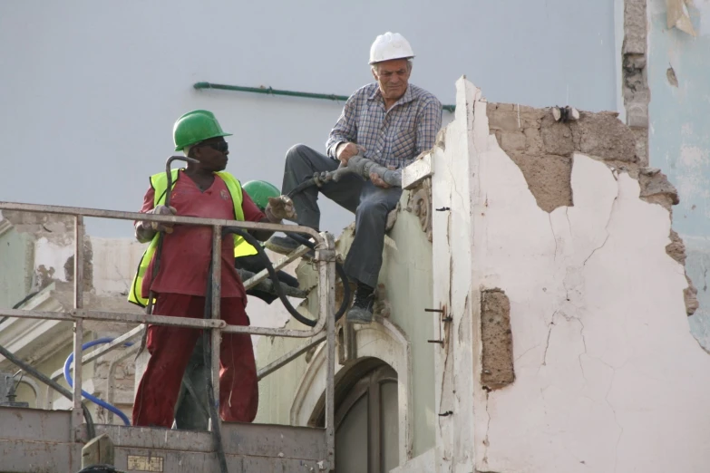 two construction workers standing on top of an old building
