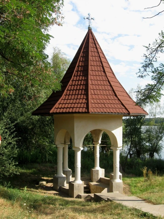 a white and brown octagonal structure sitting in the middle of a forest