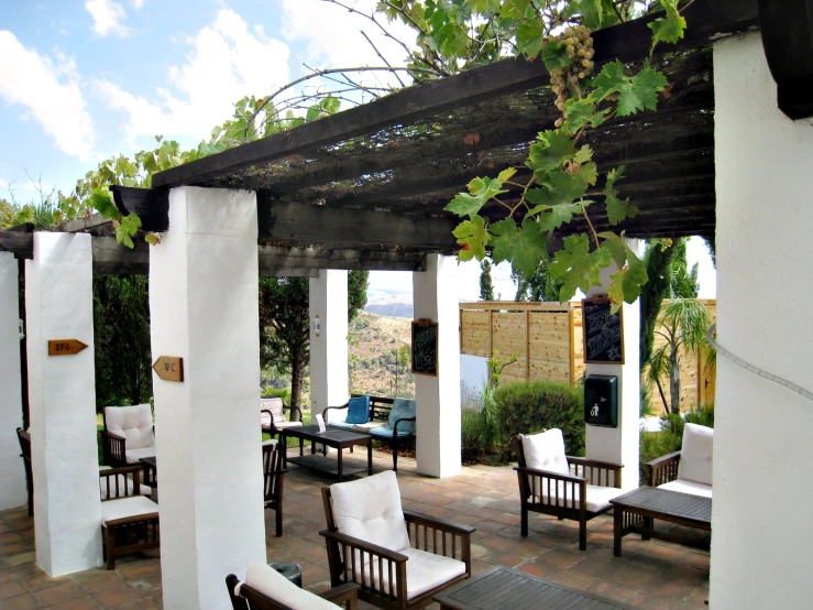 an outdoor room with wood seating and white columns