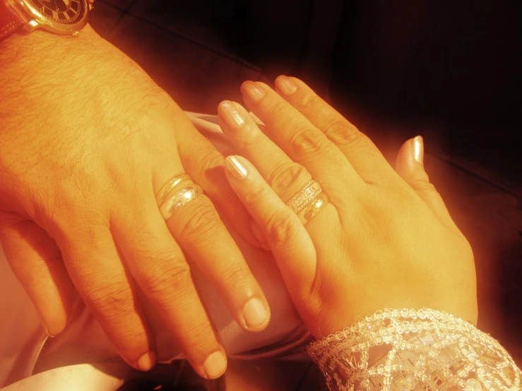 two people holding hands with some gold on their fingers