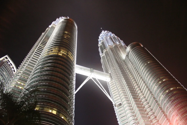 view from ground of two tall skyscrs lit up at night