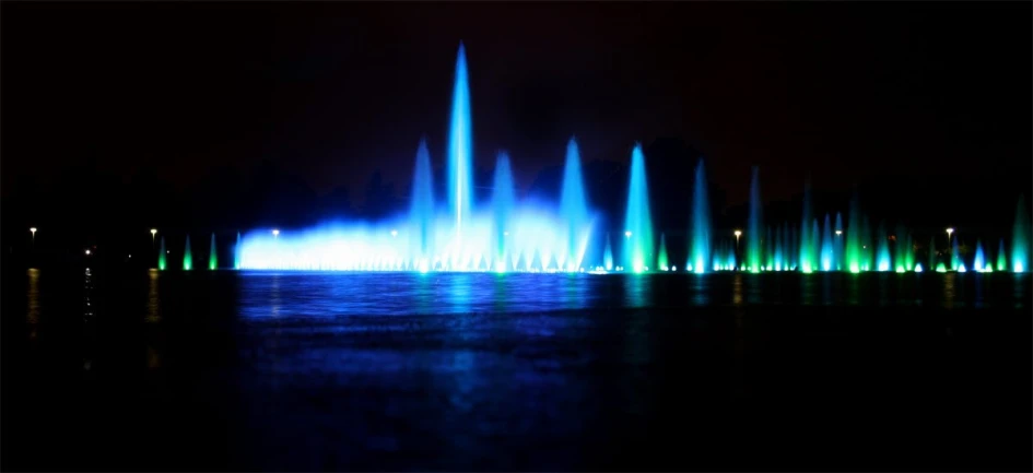 multiple colored fountains with lights reflecting off the water