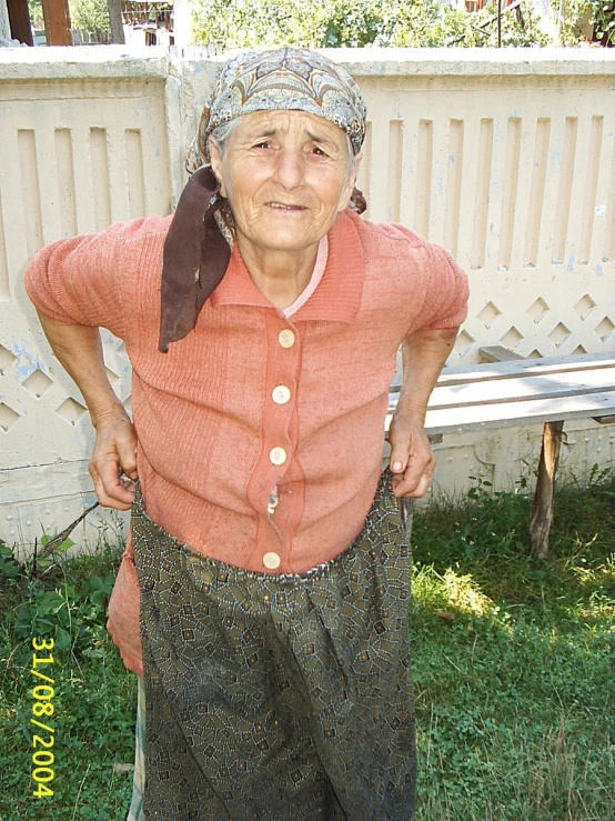 an old woman standing on grass holding a wooden stick