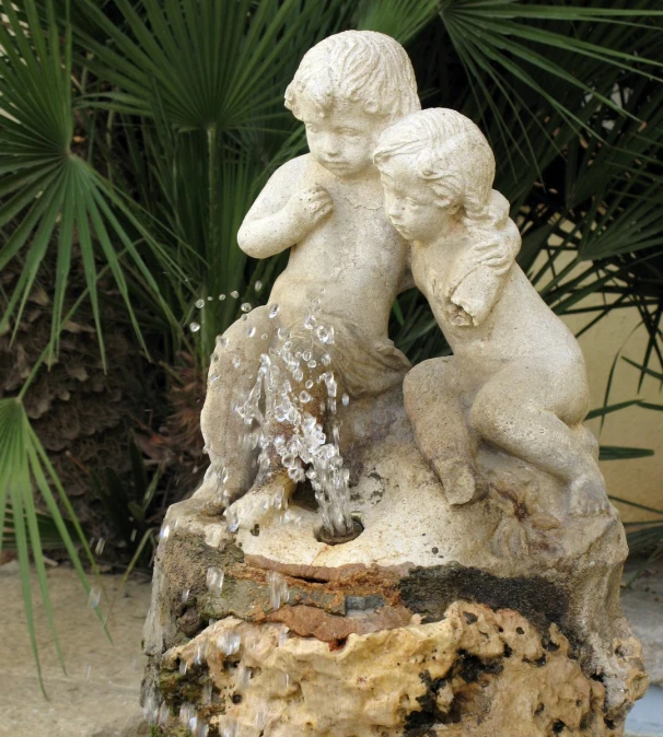 two children sitting on the rocks beside a fountain