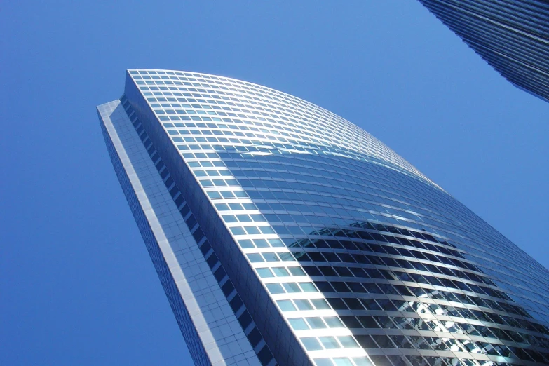 a tall building with windows sitting in the middle of a blue sky