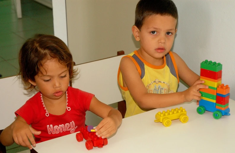 two children play with different toy vehicles on the table