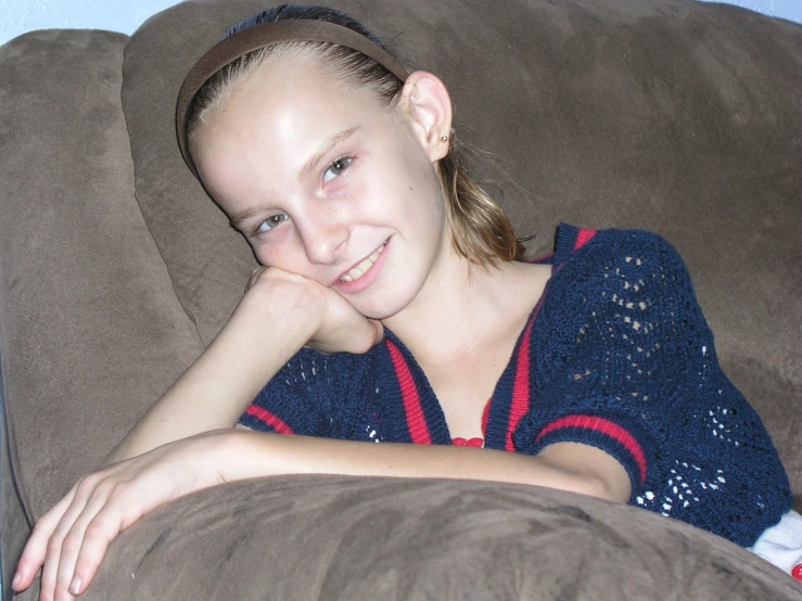 a woman laying on top of a couch holding her chin