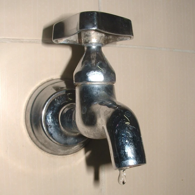 a chrome faucet running through a bathroom wall