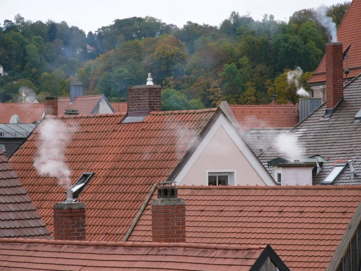 several rooftops with chimneys emitting out smoke