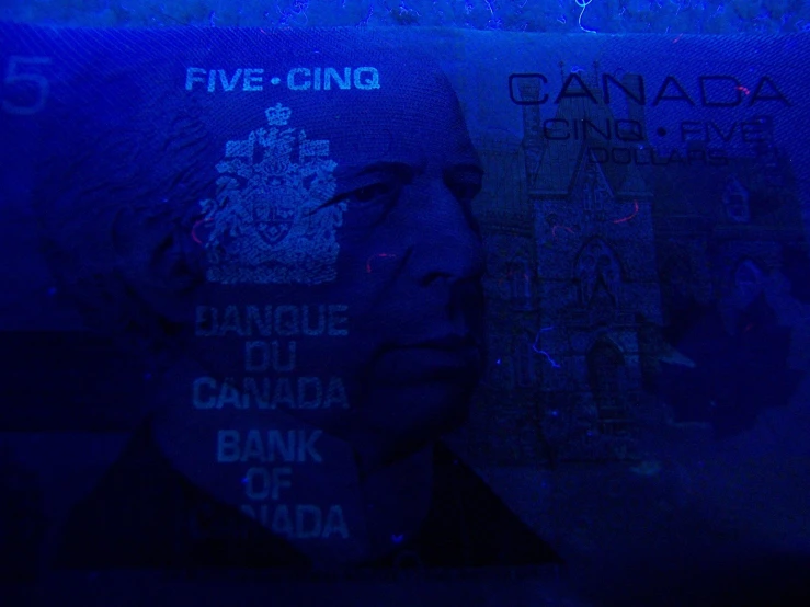 a man wearing a hat and jacket sitting in front of a blue lit wall