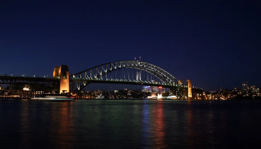 a bridge over water with lights in the distance