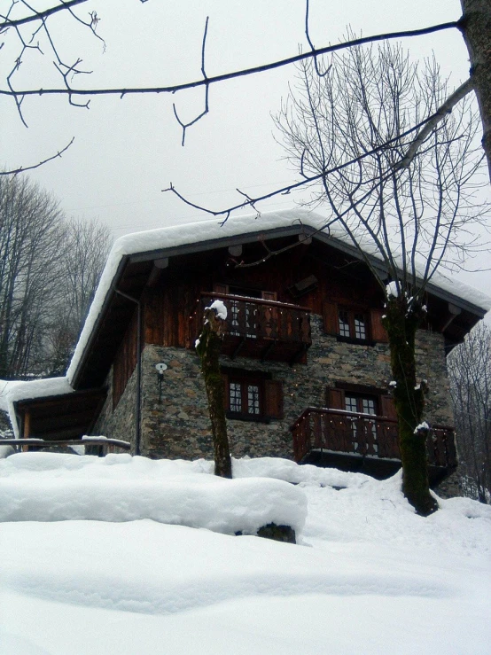 a house sitting in the snow next to trees