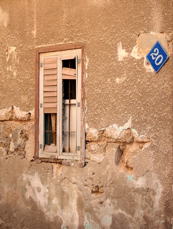 a corner of a building with an old window and no other windows