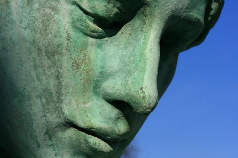 the face and shoulders of a statue against the sky