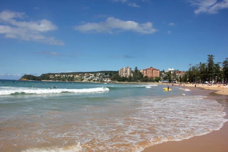 a beach with waves crashing on top of it and people swimming in the ocean