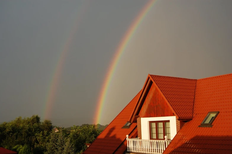 two rainbows above a red house with white trim