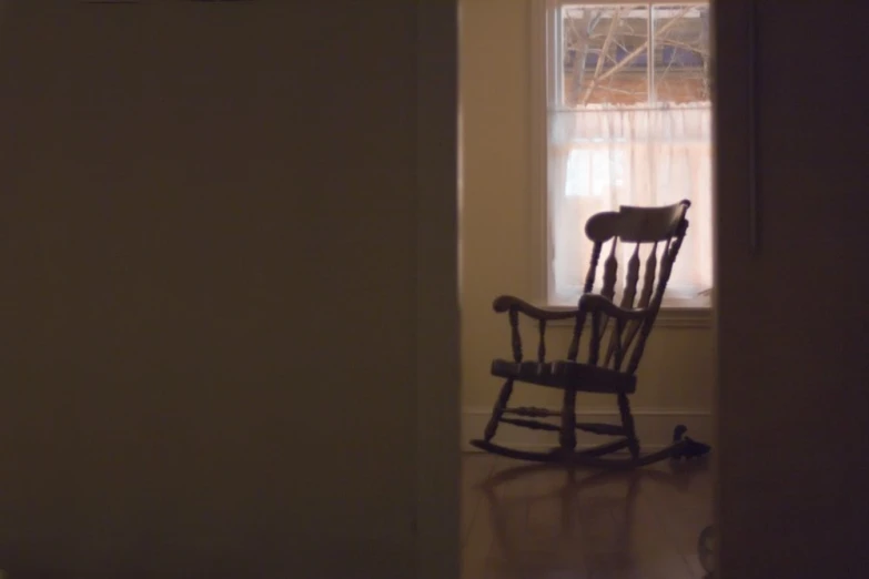 a wooden rocking chair in the corner of an empty room