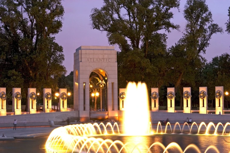 a fountain at night in the middle of a park