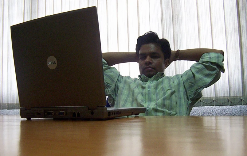 man is sitting behind a laptop on the table