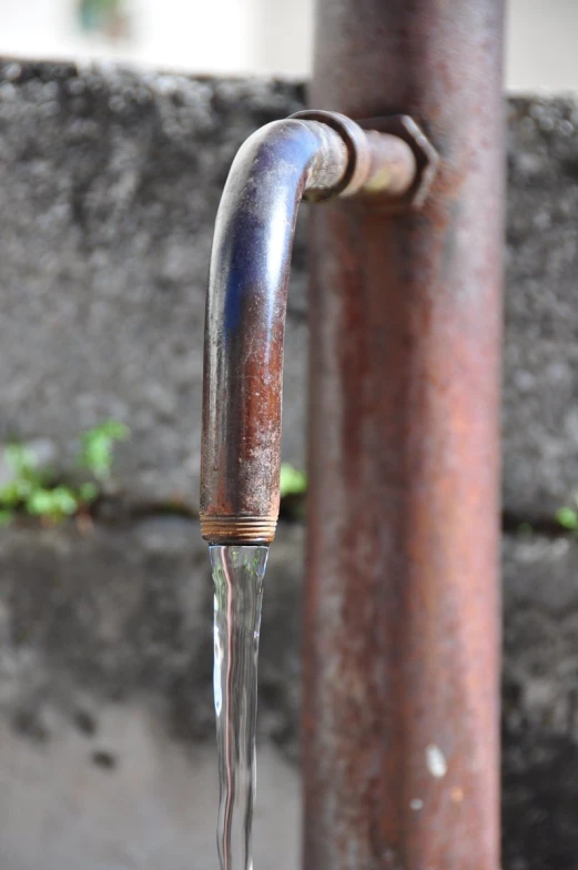 a water hose flowing out of the top of a metal pipe