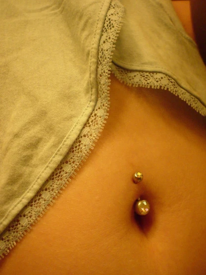 there is a shiny gold piercing in the stomach of a girl