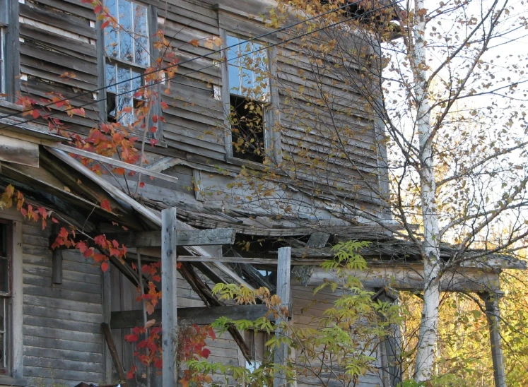 the front of an old rundown building with fall leaves